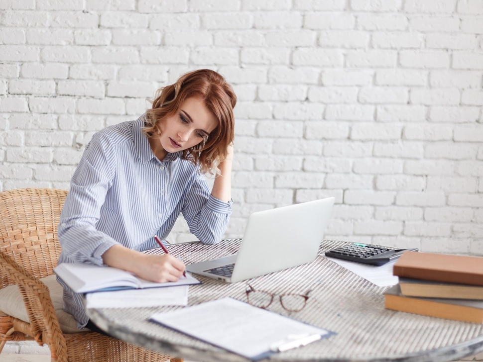 Woman freelancer female hands with pen writing on notebook at home or office